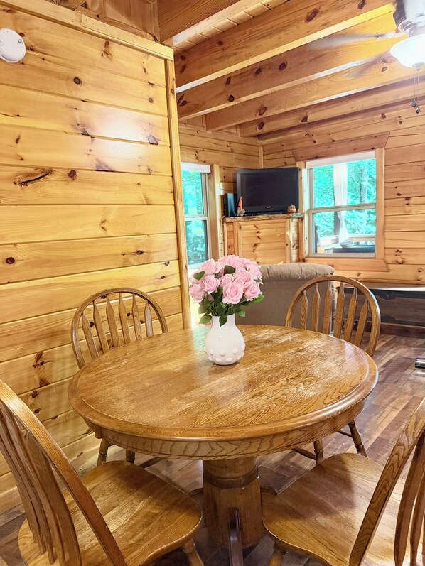 Un intérieur en bois avec une table de salle à manger ronde, des chaises et un vase rempli de fleurs.