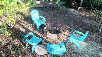 A forested area with a seating arrangement consisting of three chairs and a table.