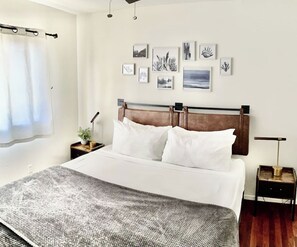 A neatly arranged bedroom with a bed, bedside tables, and wall art. - <2 min to Beach! Kihei Condo w/ Ocean View and AC (Kihei)