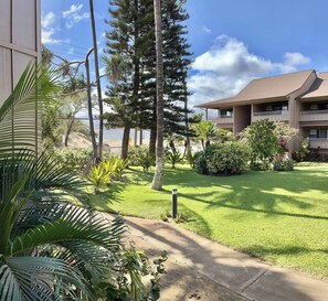 A hotel with a well-maintained lawn, a variety of trees, and a clear view of the ocean. - <2 min to Beach! Kihei Condo w/ Ocean View and AC (Kihei)