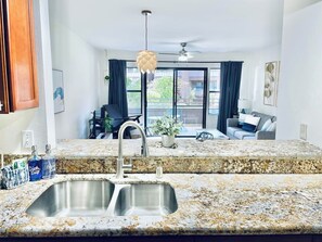 A kitchen with granite countertops, a double sink, and a ceiling fan. - <2 min to Beach! Kihei Condo w/ Ocean View and AC (Kihei)
