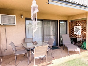 An outdoor patio with a table and chairs, a hanging light fixture, and a sliding glass door.