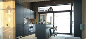 A modern kitchen with a built-in oven, a coffee machine, and a bar area with stools. - Mountain cabin with beautiful views at 1000m (Ål)