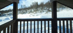 Eine Holzterrasse mit Blick auf eine verschneite Landschaft und Bäume.