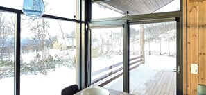 A room with large windows, a wooden deck, and a view of a snowy landscape. - Mountain cabin with beautiful views at 1000m (Ål)