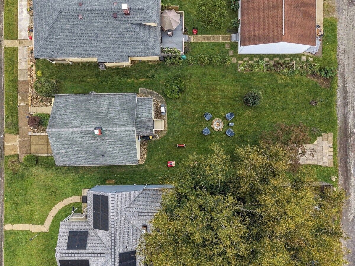 A residential area with multiple houses, a paved driveway, and a grassy lawn.