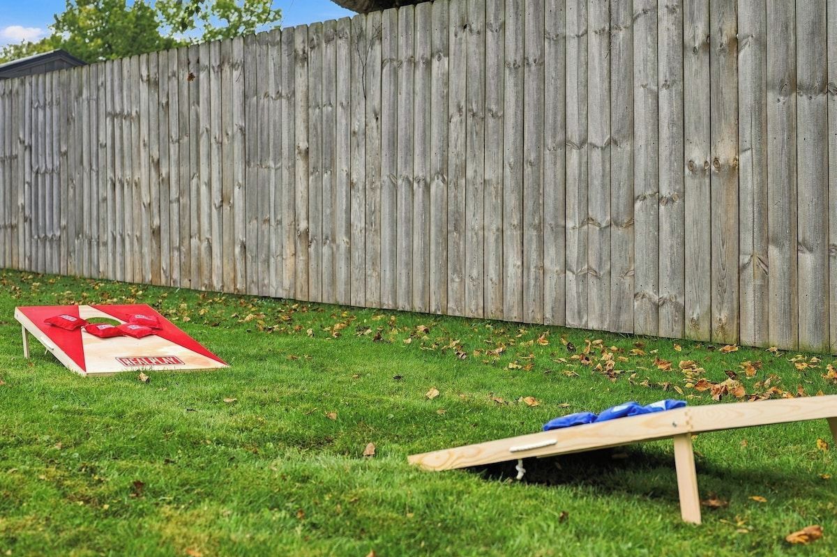 A wooden fence, a red and white object on the grass, and a wooden structure.