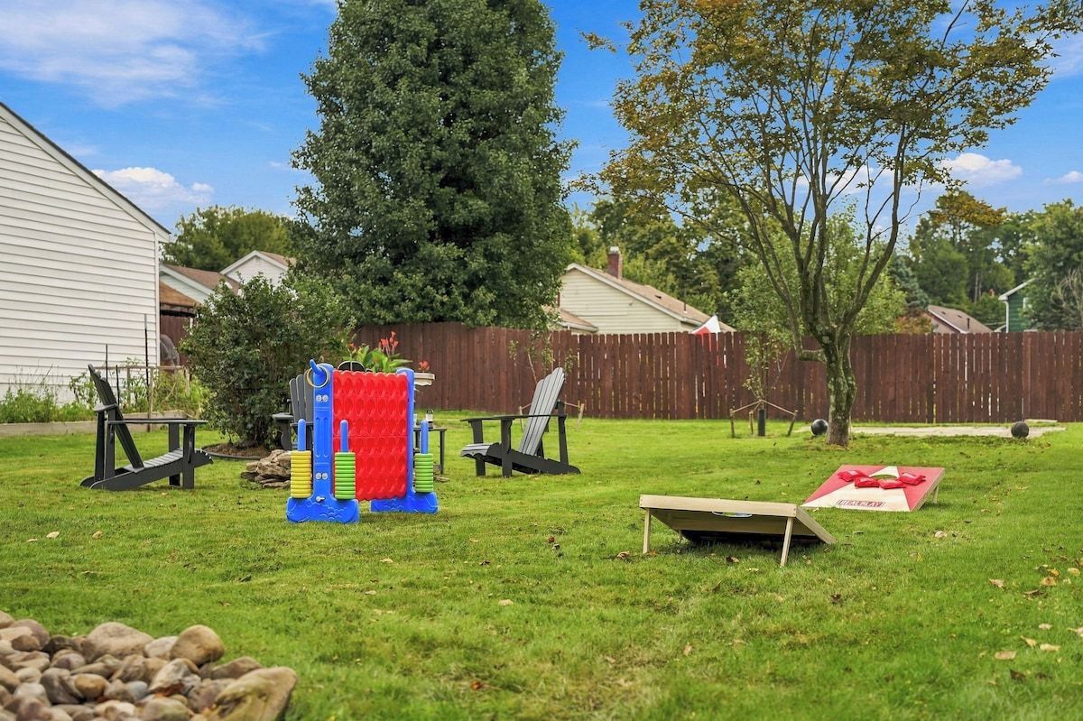 A backyard with a play structure, two chairs, a picnic table, and a small tree.