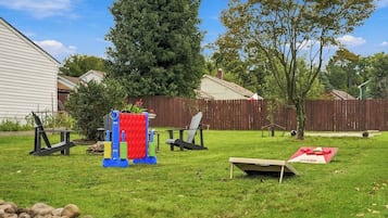 A backyard with a play structure, two chairs, a picnic table, and a small tree.