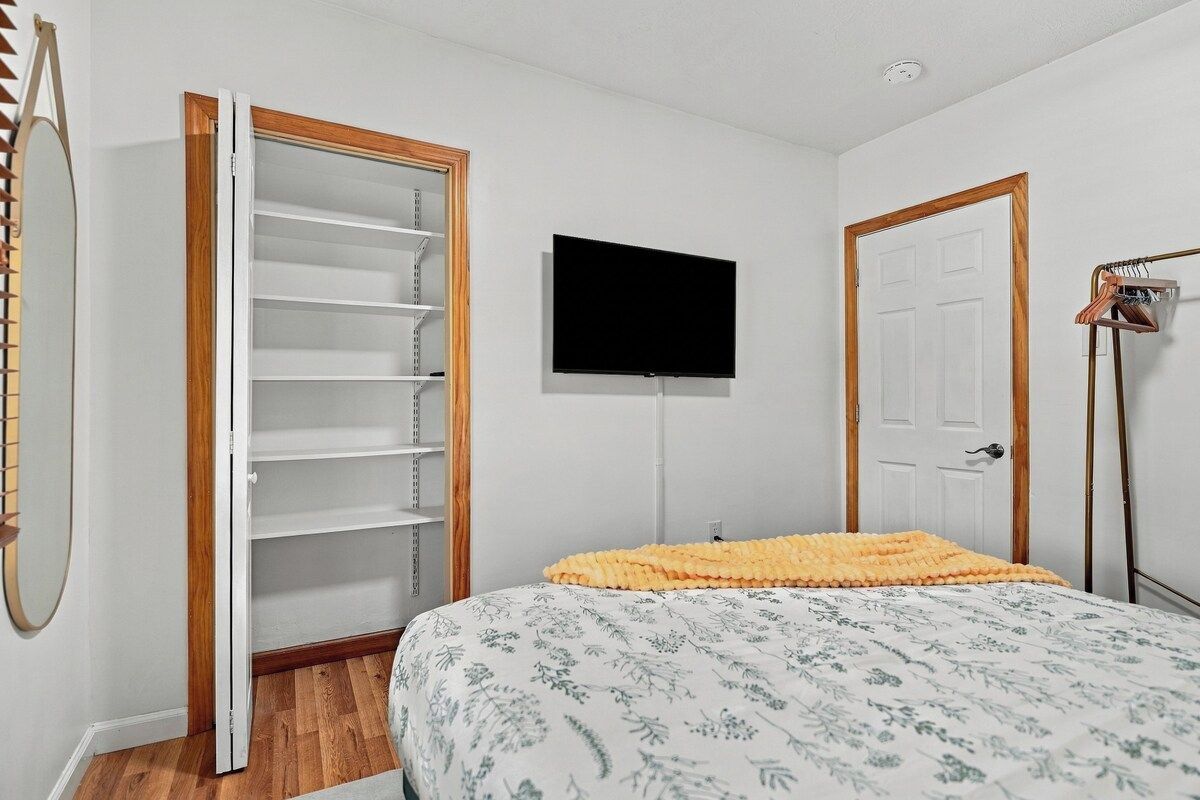 A bedroom with a bed, a wardrobe, a television, and a door.