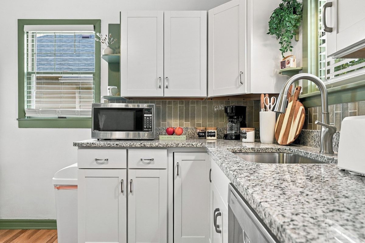 A kitchen with white cabinets, a microwave, a coffee maker, and a sink.
