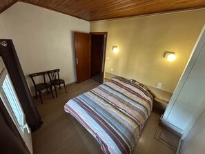 A bedroom with a bed, a chair, a door, and two wall-mounted lights. - Charming two-bedroom apartment in the heart of Formiguères (Formiguères)