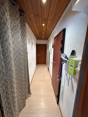 A hallway with a wooden ceiling, patterned wallpaper, and a door with a coat hanging on it. - Charming two-bedroom apartment in the heart of Formiguères (Formiguères)