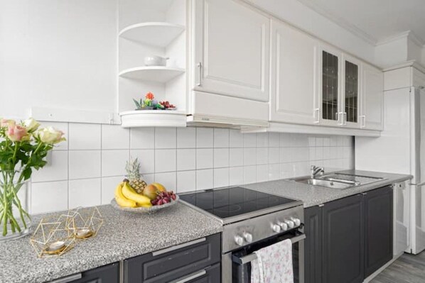 A modern kitchen with white cabinets, a granite countertop, and a built-in stove.