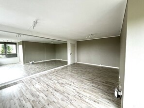 A spacious room with a large mirror, wooden flooring, and a door leading to another room. - Apartment in Romolslia (Trondheim)