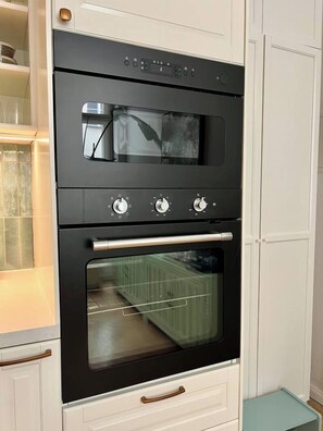 Eine Küche mit einem schwarzen Backofen, weißen Schränken und einer Glastür.