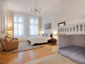 Ein Schlafzimmer mit Etagenbett, einem Einzelbett, einem Sessel, einem Nachttisch und einer Lampe.