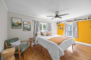 A bedroom with a bed, a chair, a small table, and a ceiling fan. - Stay Next 2 Duke Hospital, Fire Pit & King Bed (Durham)