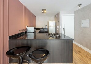 Een moderne keuken met een centraal eiland, barkrukken, een koelkast en een fornuis.