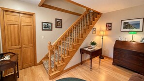 A staircase with wooden railings, a wooden dresser, a table with a lamp, and framed pictures on the walls. - Lakefront home on Sebec Lake, 4-bedroom, 3 bathrooms (Bowerbank)