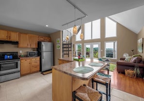 A modern kitchen with a central island, wooden cabinets, stainless steel appliances, and a view to the outdoors. - Entire Lakefront Cabin - 2 Private 1BR Suites - With Smoky Mountain View sunrise (Sevierville)