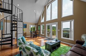 A spacious living area with a staircase, a dining area, and large windows offering views of the outdoors. - Entire Lakefront Cabin - 2 Private 1BR Suites - With Smoky Mountain View sunrise (Sevierville)