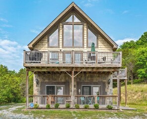 A two-story wooden house with a balcony, stone foundation, and a clear sky. - Entire Lakefront Cabin - 2 Private 1BR Suites - With Smoky Mountain View sunrise (Sevierville)