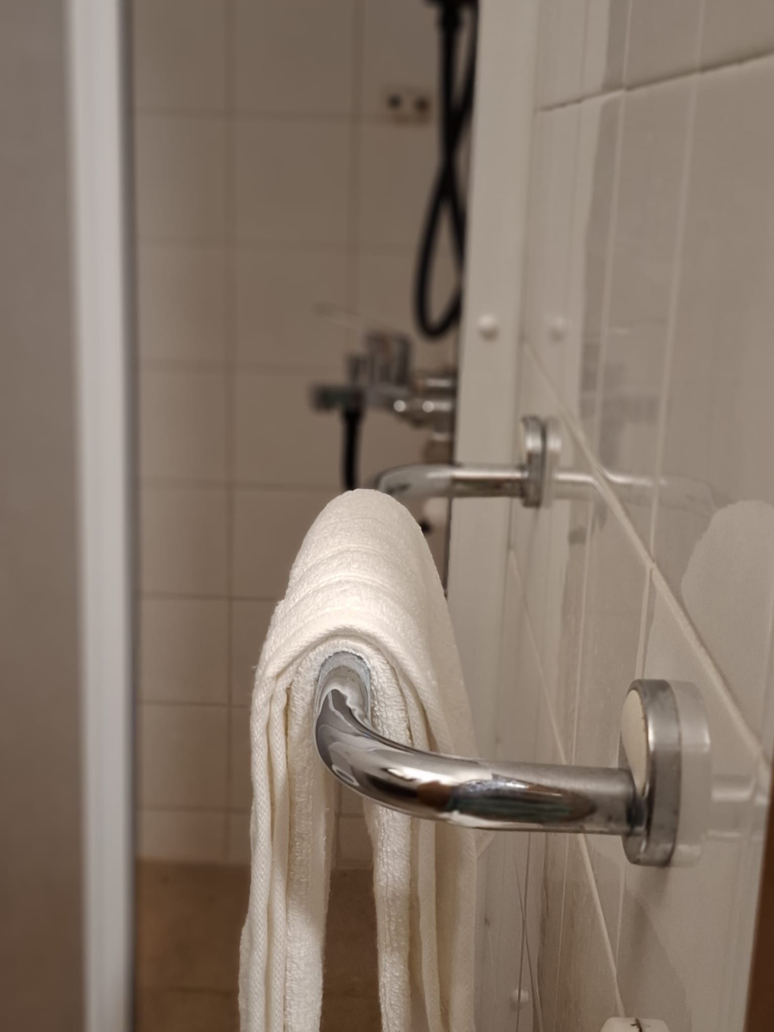 A bathroom with a towel rack holding a white towel.