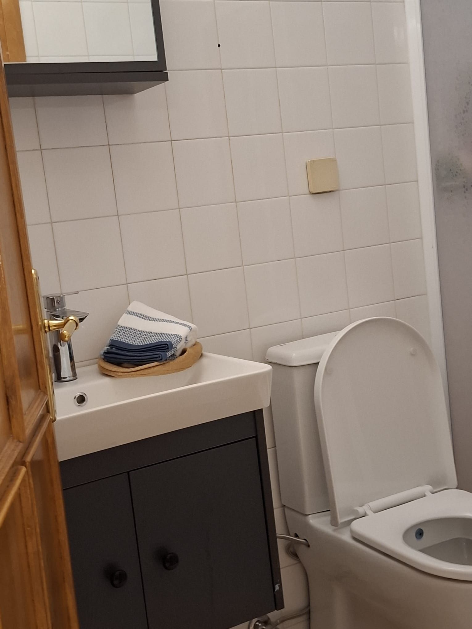 A bathroom with a white toilet, a sink with a towel holder, and a cabinet below.