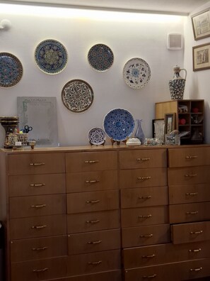 A room with multiple drawers and a wall decorated with various plates and a vase.