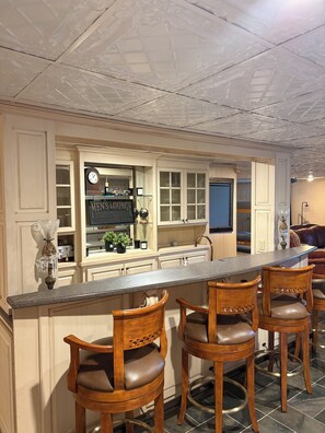 A kitchen with a bar area, wooden chairs, and a clock. - The Ultimate Masters Stay - Manor + Event Venue in Augusta - near Airport & 520 (Augusta)