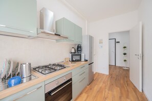 A modern kitchen with a gas stove, microwave, and a coffee machine. There are cabinets, a dishwasher, and a wooden countertop. - Apartment Between Parma and Rez, on the Via Emilia, a region rich in gastronomy and culture (Sant'Ilario d'Enza)
