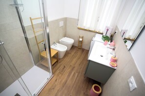 Een moderne badkamer met een douche, toilet, wastafel en een klein houten plankje.