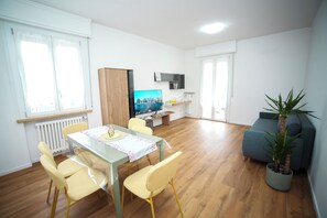 A modern living room with a dining area, a TV, and a potted plant. - Apartment Between Parma and Rez, on the Via Emilia, a region rich in gastronomy and culture (Sant'Ilario d'Enza)