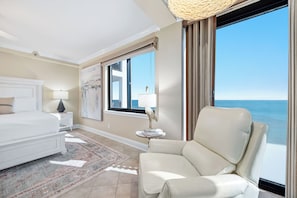 A hotel room with a bed, a chair, a window with a view of the sea, and a painting on the wall. - "Broadmoor #705" --- New! Beachfront 3BR, Stunning Gulf Views, Pool, Hot Tub (Orange Beach)
