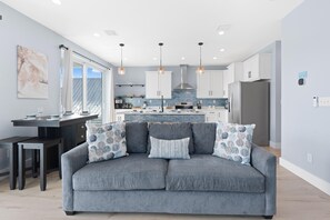 A modern kitchen with white cabinets, a central island, and pendant lighting. - The Turtle Nest (Fort Myers Beach)