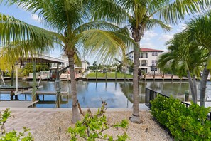 A waterfront property with a canal, palm trees, and a building with a red roof. - Oasis on Ohio Ave (Fort Myers Beach)