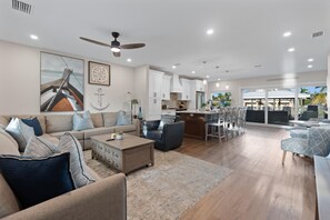 A spacious living area with a sofa, coffee table, and dining area with chairs. - Oasis on Ohio Ave (Fort Myers Beach)