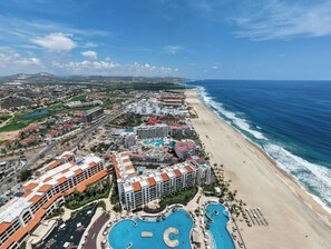 A coastal resort with multiple swimming pools, beachfront villas, and a view of the ocean. - Beachfront 2BR Penthouse, Private Rooftop Jacuzzi (San José del Cabo)