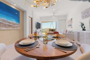 A dining area with a round wooden table, white plates, and clear glasses. - Beachfront 2BR Penthouse, Private Rooftop Jacuzzi (San José del Cabo)
