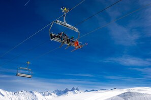 A ski lift carrying skiers and a chairlift in a snowy mountainous area.
