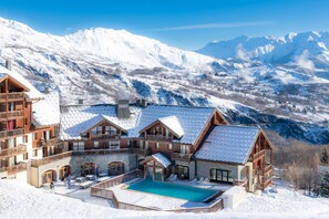 A snow-covered mountain resort with a pool and multiple buildings.