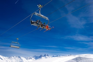 A ski lift carrying skiers and a chairlift in a snowy mountainous area.