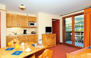 A kitchen with wooden cabinets, a microwave, and a dining area with a table set for two.
