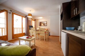 A compact hotel room with a dining area, kitchenette, and a bed.