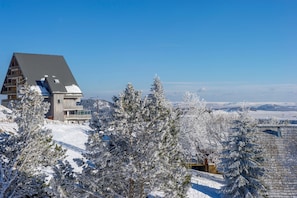 A snow-covered mountain lodge with a prominent wooden structure and a clear view of the surrounding snowy landscape.