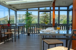 Een zonnig terras met een eettafel, stoelen en een potplant.