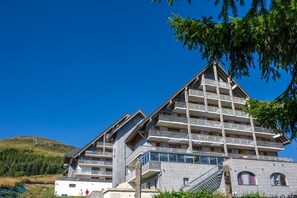 A multi-story hotel with a steeply pitched roof, balconies, and a stone facade.