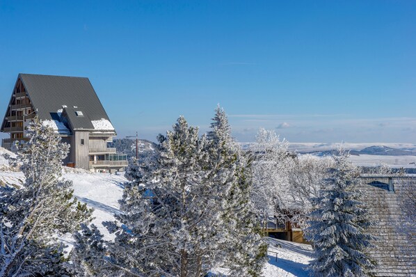 A snow-covered mountain lodge with a prominent wooden structure and a clear view of the surrounding snowy landscape.