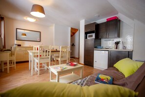 A compact living space with a dining area, kitchenette, and a sofa with a pillow.